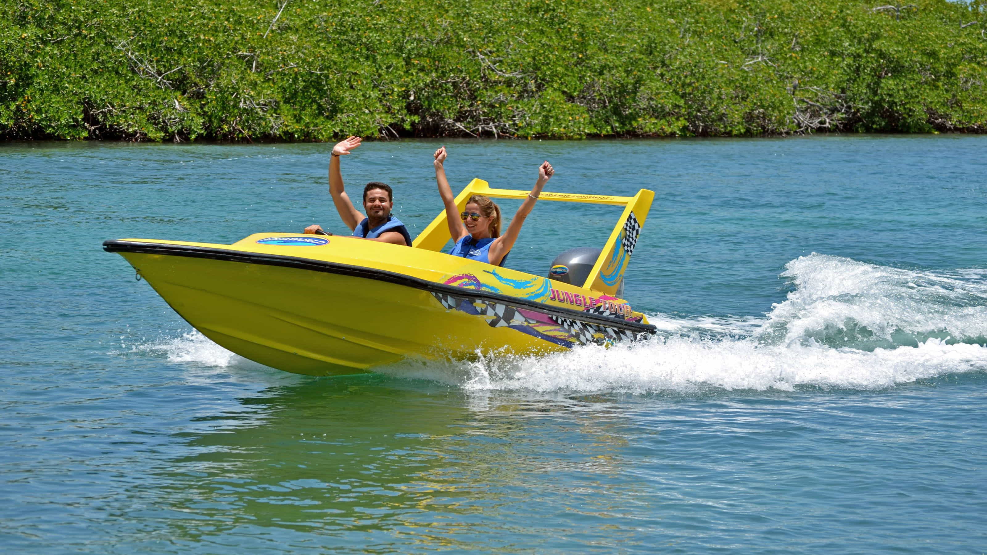 Couple happily riding a yellow speed boat through mangroves on a Jungle Tour in Cancun